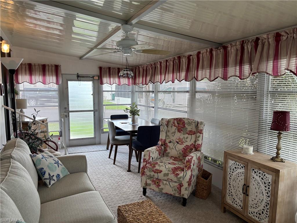 Enclosed sunroom with ceiling fan and integrated lighting, multiple windows with blinds, and a glass-paneled door
