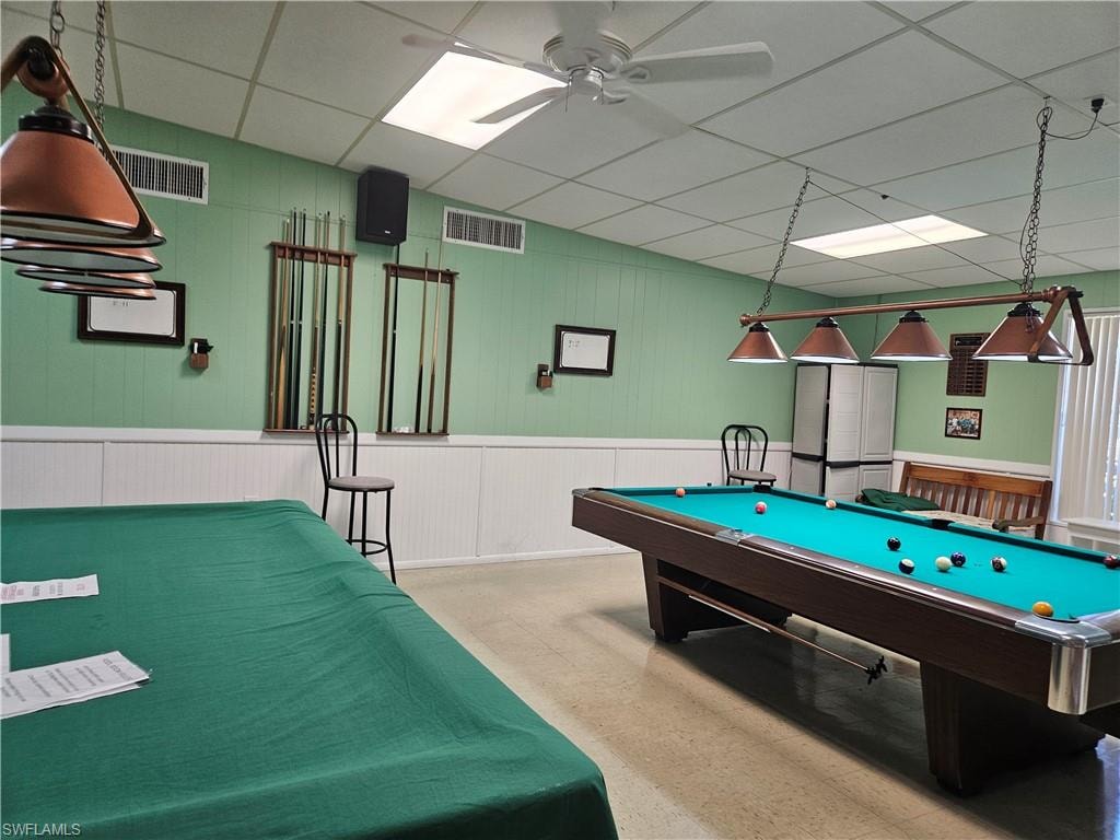 Recreation room featuring billiards, a drop ceiling, a ceiling fan, and wood walls