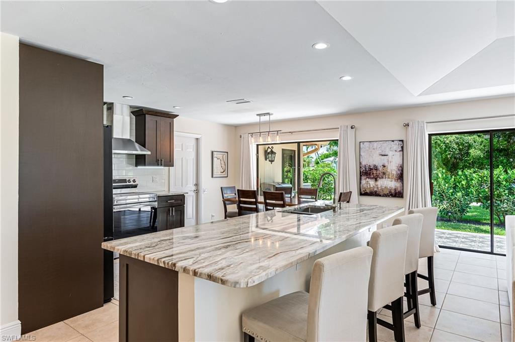Kitchen with sink, dark brown cabinets, plenty of natural light, and wall chimney exhaust hood