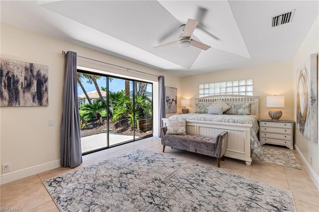 Tiled bedroom with multiple windows, ceiling fan, and access to outside