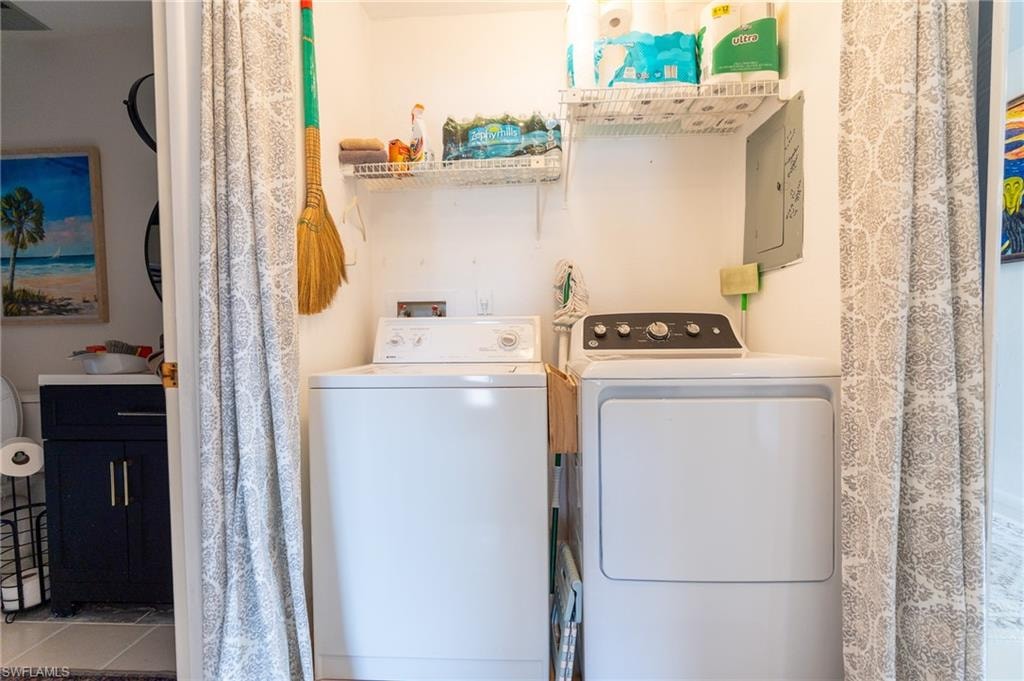 Dedicated laundry area featuring a washer and dryer, an overhead wire shelving unit, and a visible electrical panel