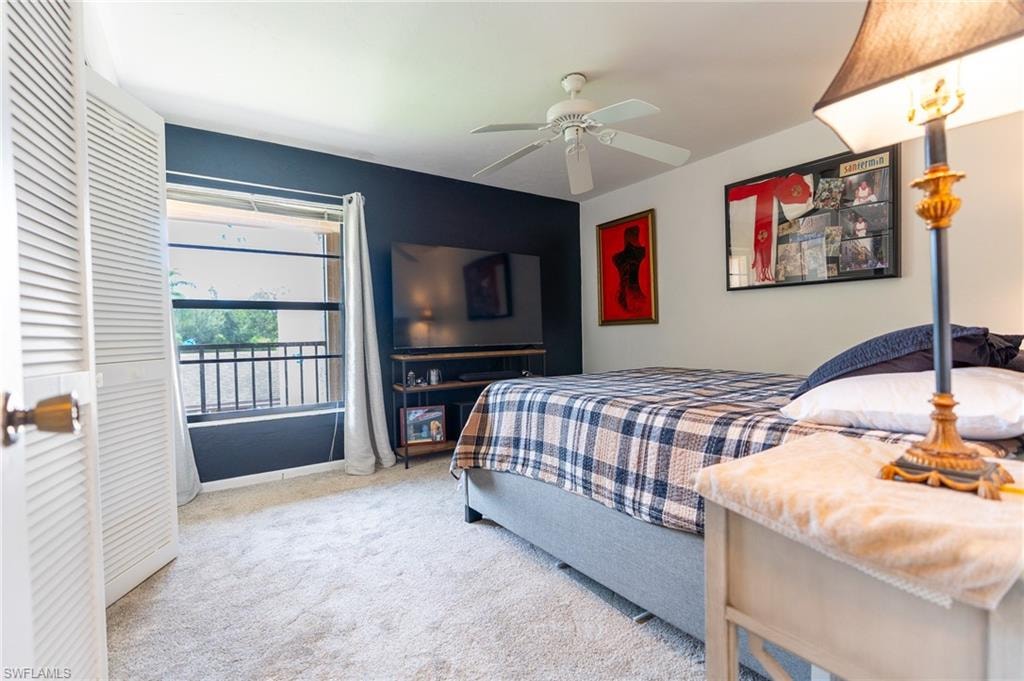 Bedroom featuring light gray carpeting, a dark accent wall, and a ceiling fan