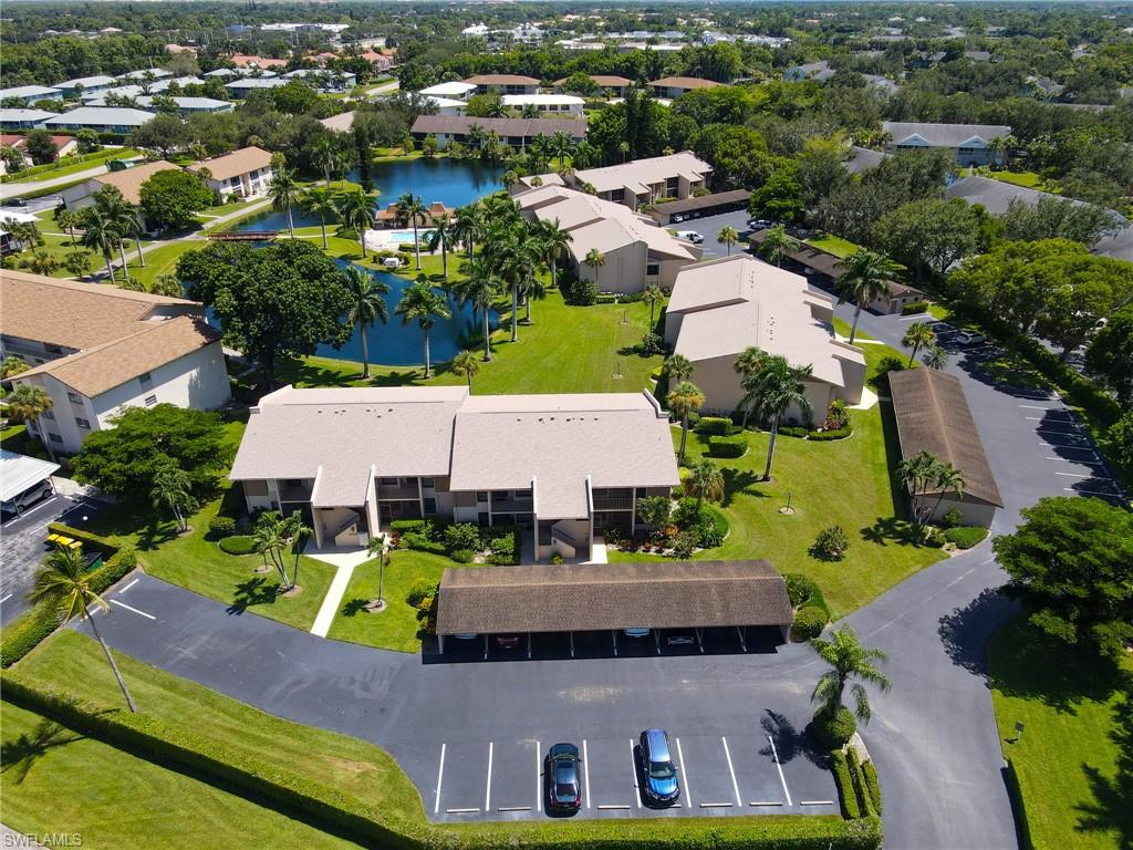 Lush landscaping, a water feature, multiple multi-story residential buildings, and dedicated parking areas
