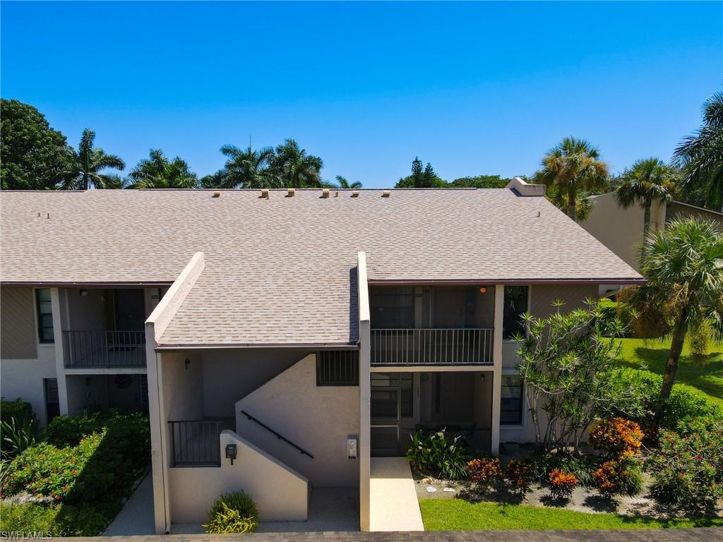 Shingle roof, two private balconies, exterior staircase, and mature landscaping