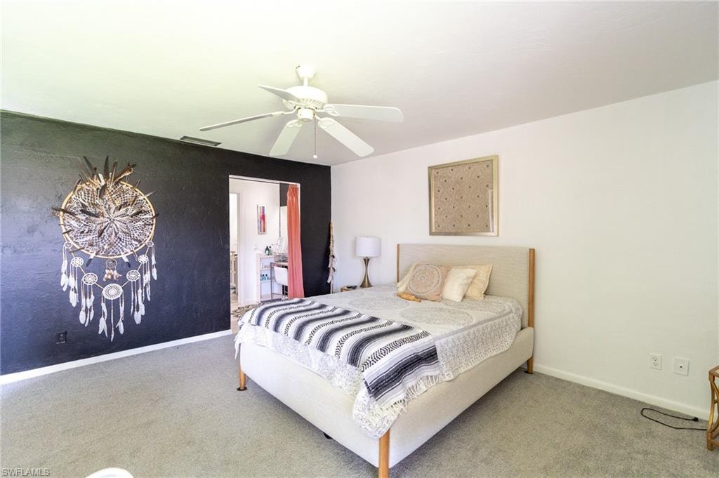 Bedroom featuring light-colored carpeting, a ceiling fan, and a contrasting accent wall
