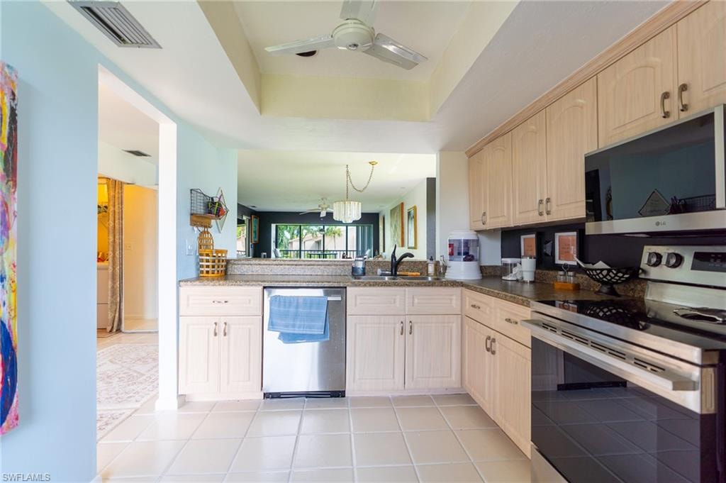 Kitchen featuring extensive cabinetry, stone-finish countertops, stainless steel appliances, and tile flooring