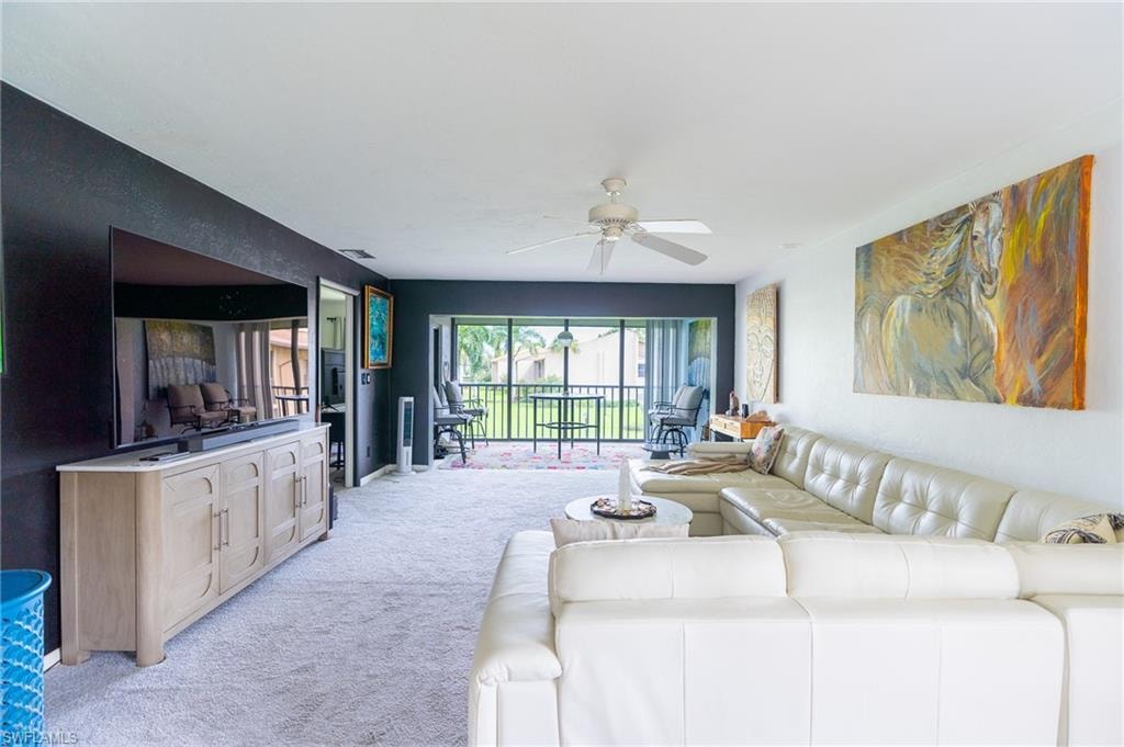 Spacious living area featuring light-toned carpeting and a ceiling fan