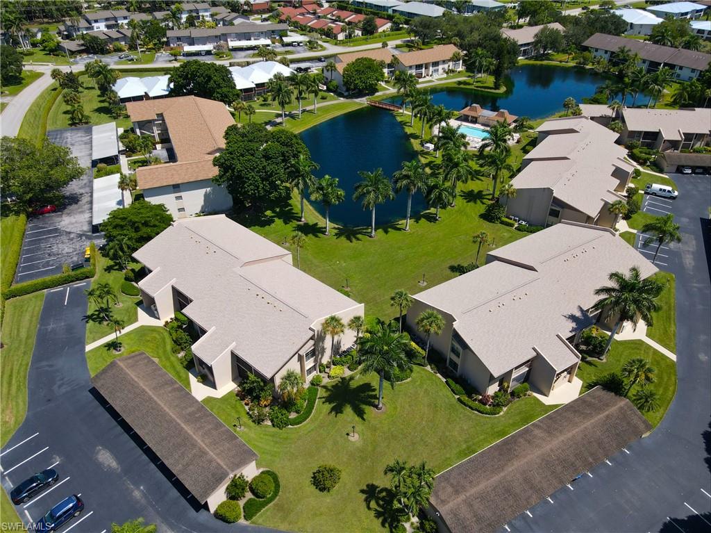 Community featuring multiple residential structures, central water features, a swimming pool, and dedicated parking areas