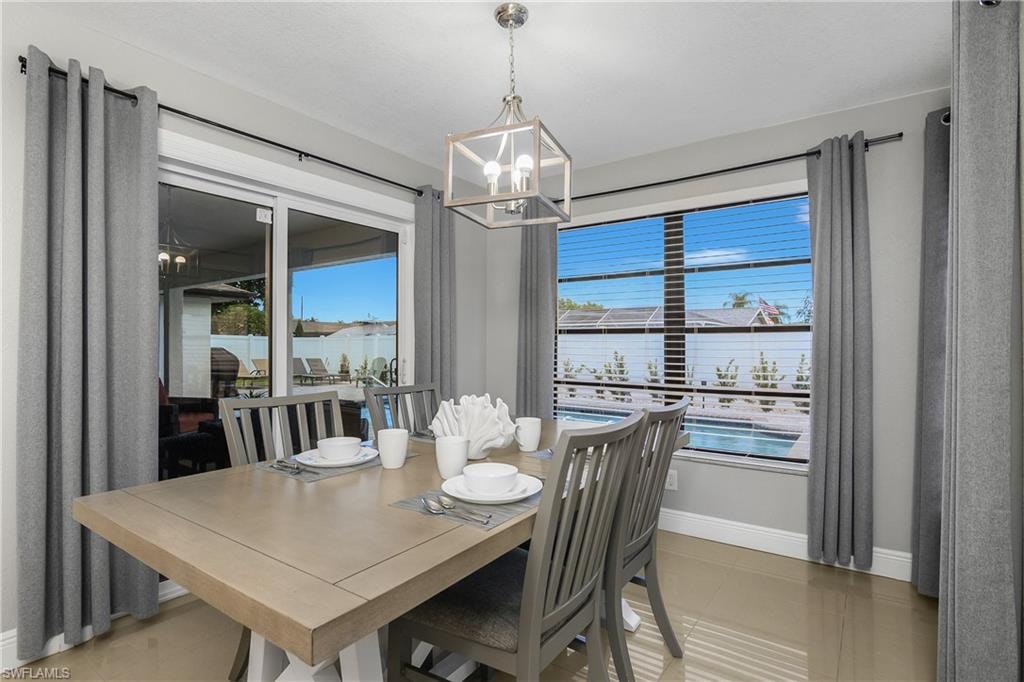 Dining area featuring a contemporary chandelier, large sliding glass doors, and a window with horizontal blinds