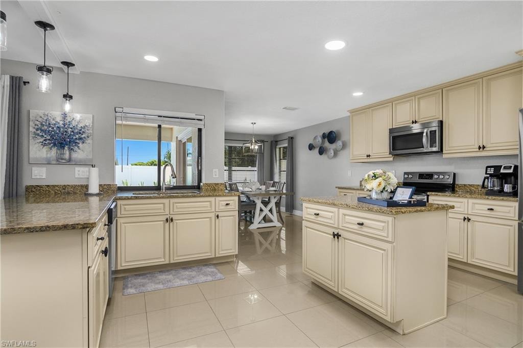 Spacious kitchen featuring cream-colored cabinetry, stone countertops, and tile flooring