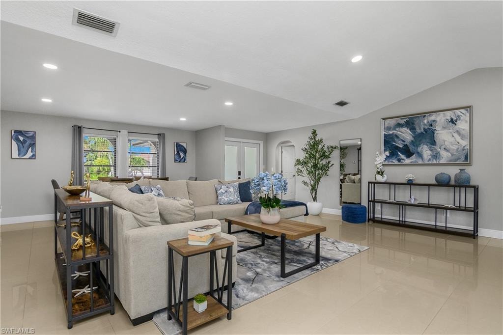 Spacious living area featuring light-toned tile flooring and recessed lighting