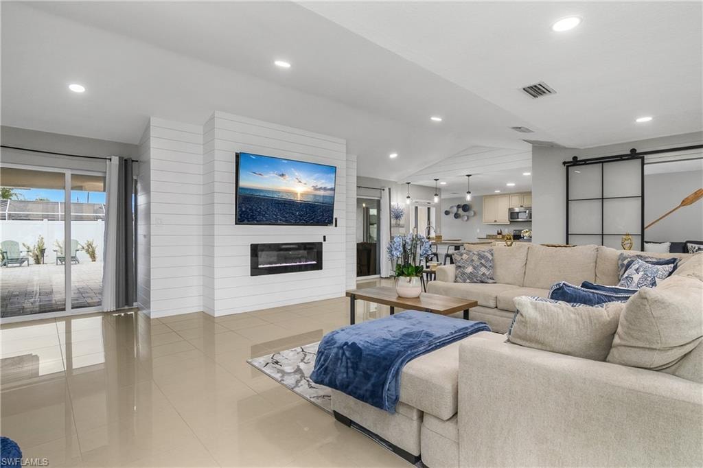 Living area featuring a shiplap accent wall with an integrated electric fireplace, polished tile flooring, and recessed lighting
