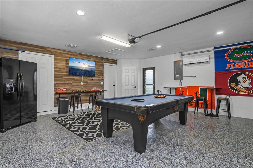 Spacious multi-purpose room featuring a pool table, wood-finish accent wall, and durable epoxy flooring