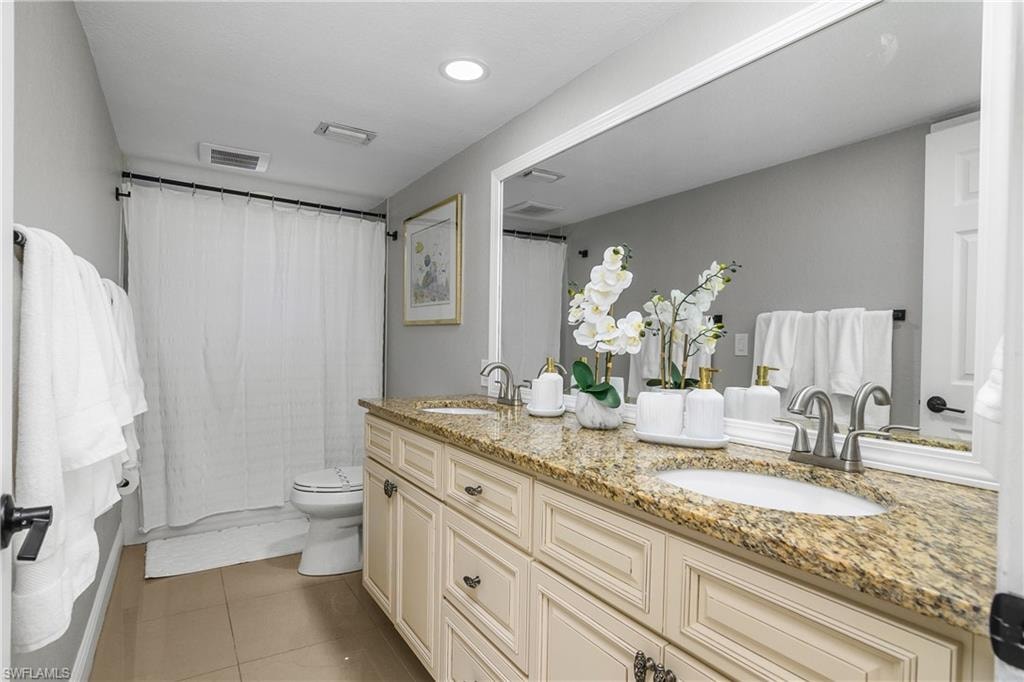Bathroom featuring a dual vanity with granite-finish countertop, undermount sinks, and brushed nickel faucets