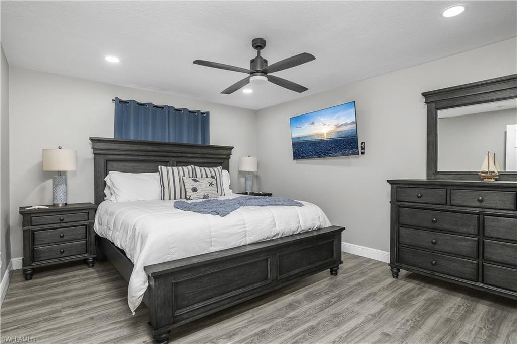 Spacious room featuring wood-finish flooring, recessed ceiling lighting, a ceiling fan, and window treatments