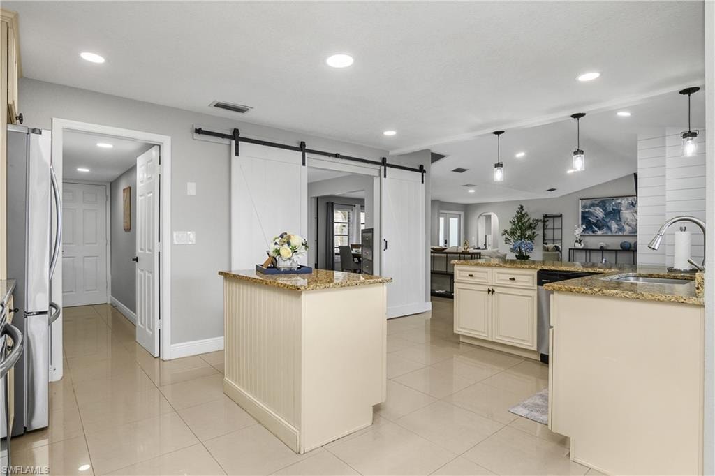 Spacious kitchen featuring tile flooring, light-colored cabinetry with granite countertops, recessed lighting, and stylish barn doors