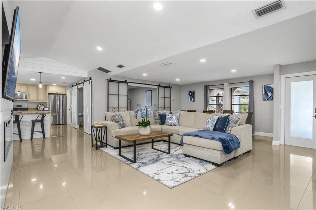 Spacious living area featuring neutral-toned tile flooring and recessed lighting