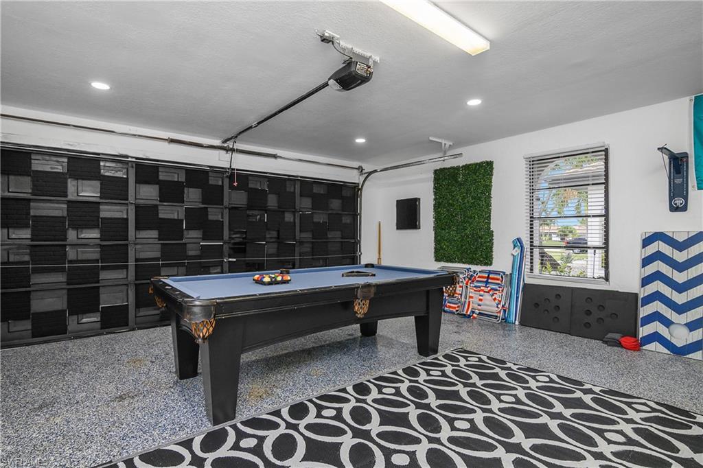 Spacious garage featuring a durable epoxy floor, recessed lighting, and a window with blinds