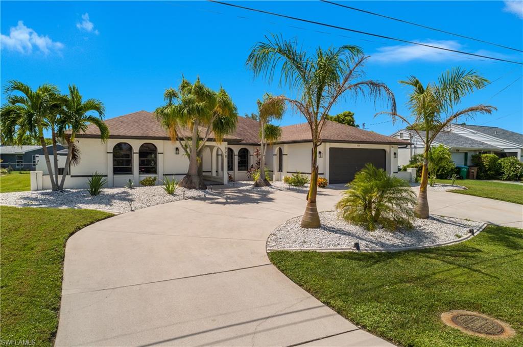 Stucco exterior with arched windows, a dark shingle roof, and an attached garage