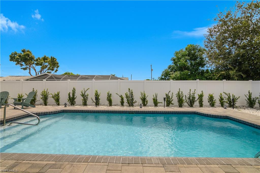 Geometric swimming pool with paver decking, integrated steps, and a handrail