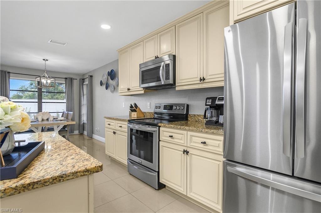 Kitchen featuring light cabinetry, granite countertops, stainless steel appliances, and tile flooring