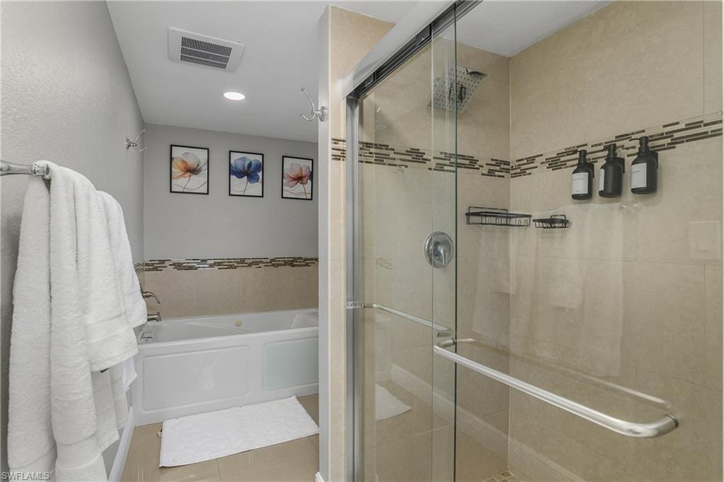 Walk-in shower with clear glass enclosure and rain showerhead, complemented by a built-in jetted tub