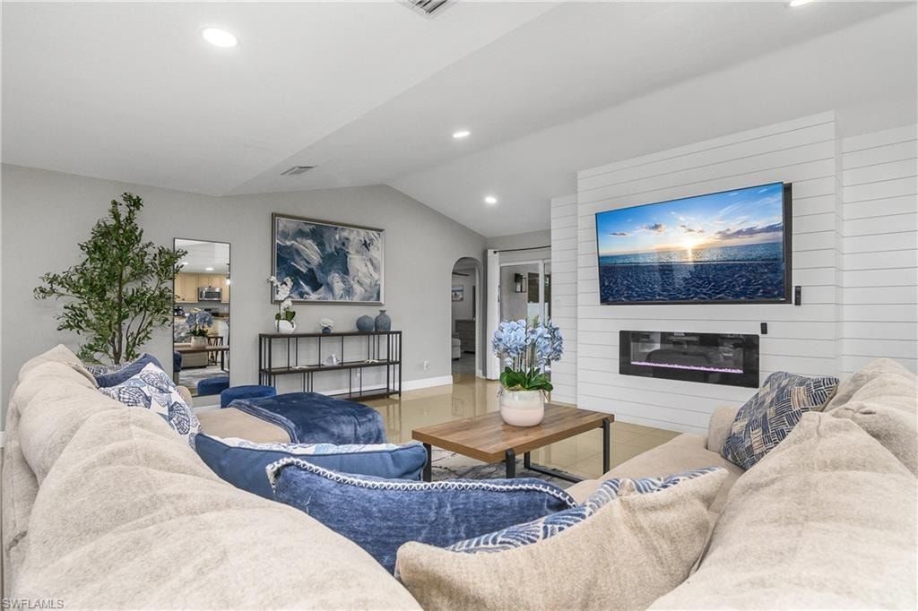 Spacious living area featuring a shiplap accent wall with an integrated electric fireplace and a large mounted television