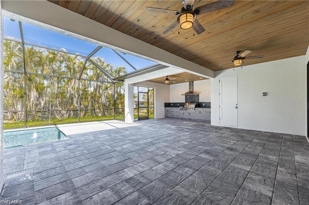View of patio with ceiling fan, grilling area, a lanai, and exterior kitchen