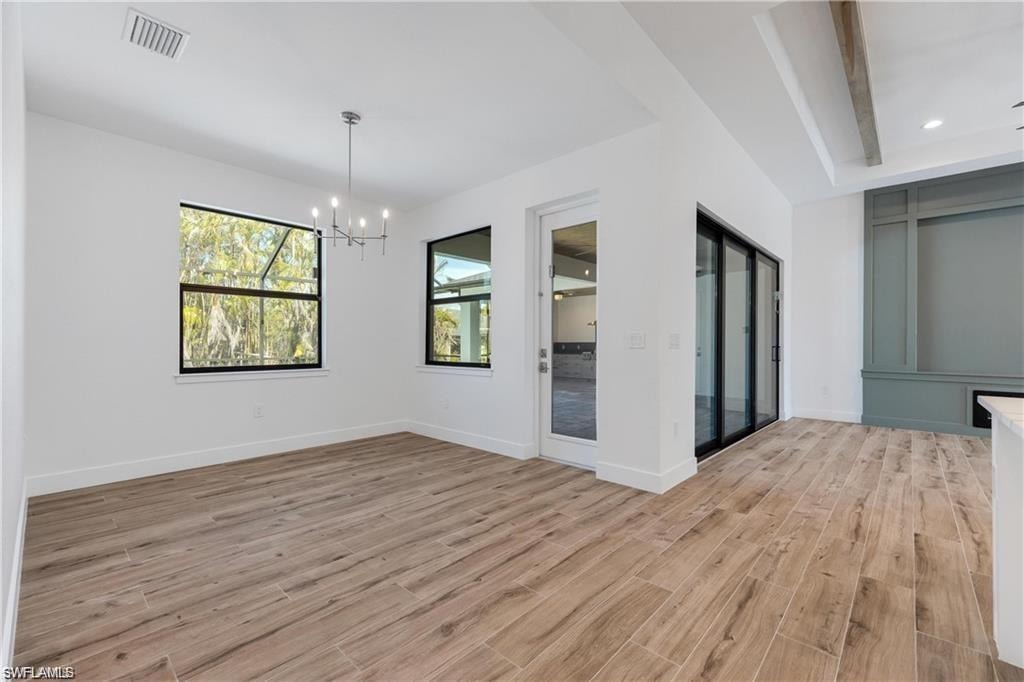 Spare room featuring an inviting chandelier and light hardwood / wood-style flooring