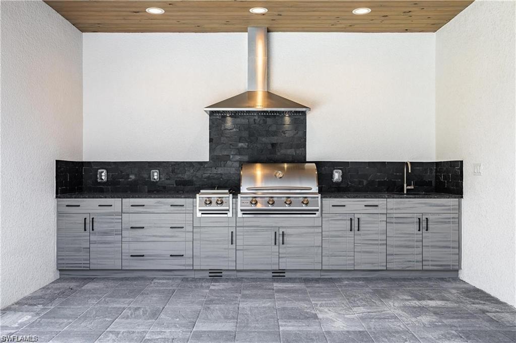 Kitchen with wooden ceiling, decorative backsplash, and wall chimney exhaust hood