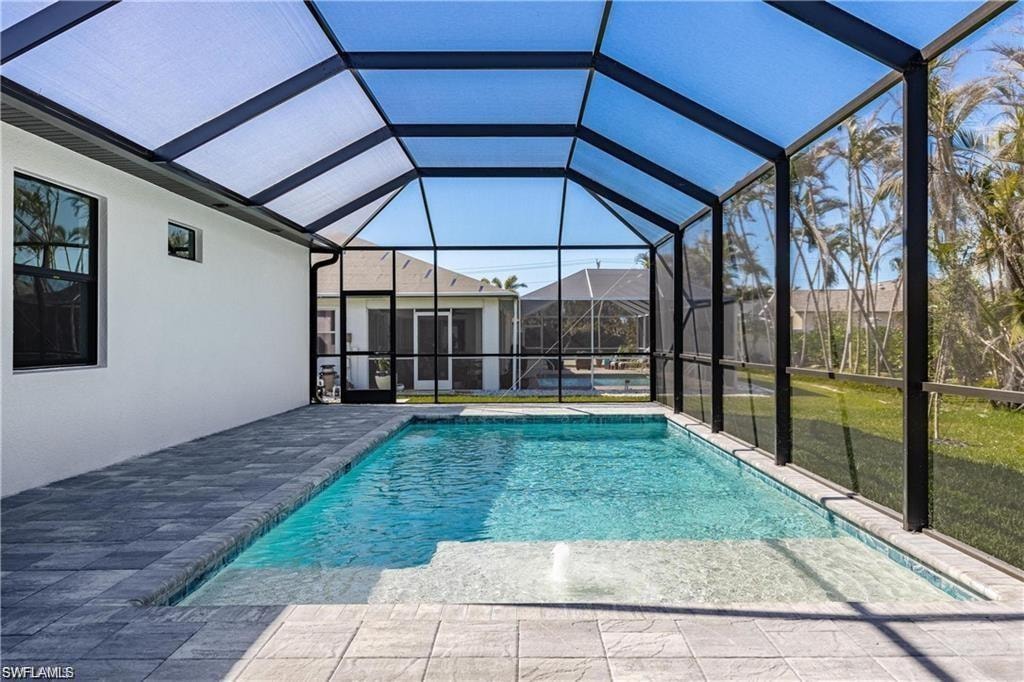 View of pool featuring a patio area and glass enclosure