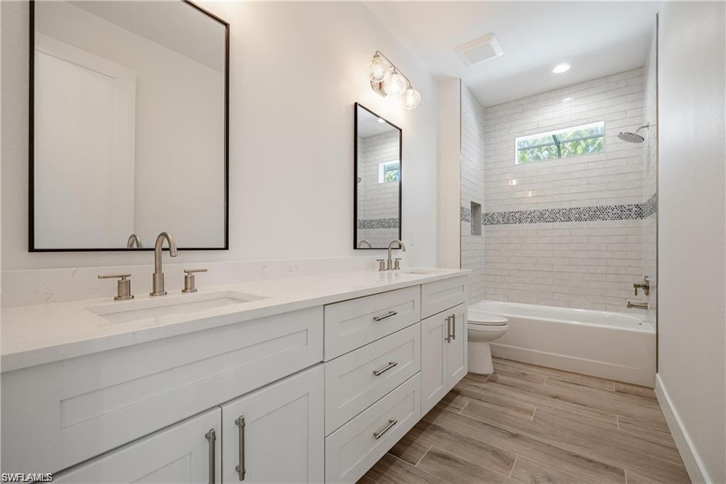 Full bathroom featuring tiled shower / bath, vanity, and toilet
