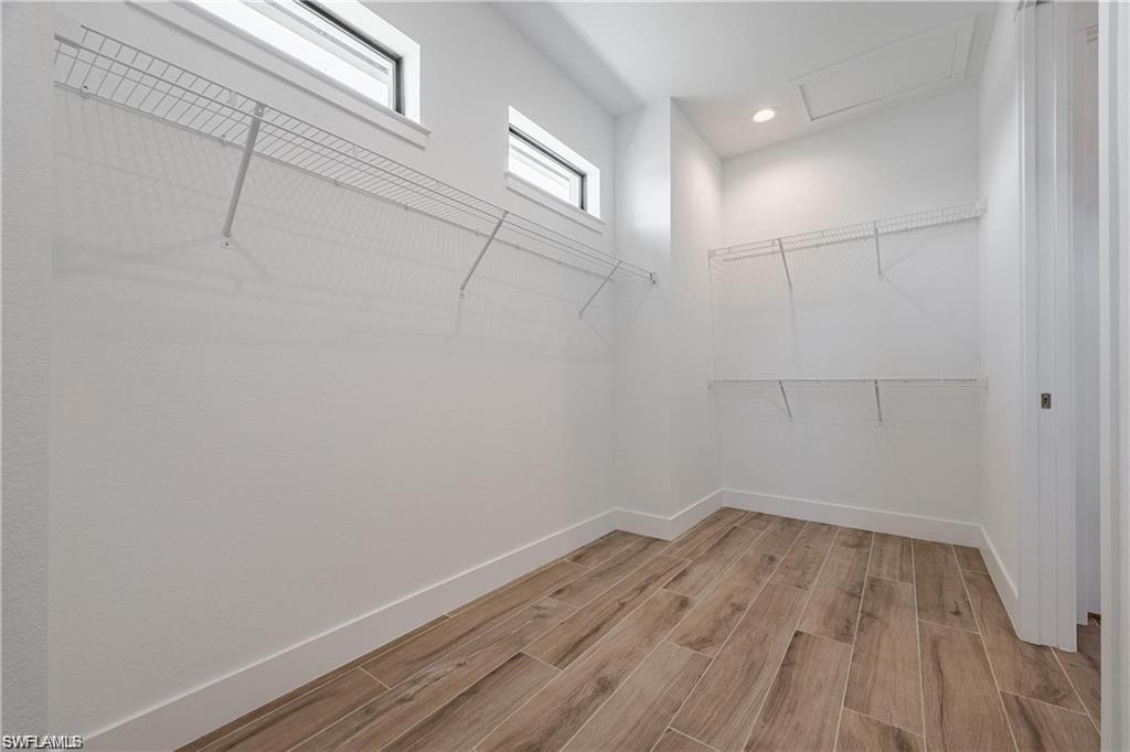 Walk in closet with light hardwood / wood-style flooring