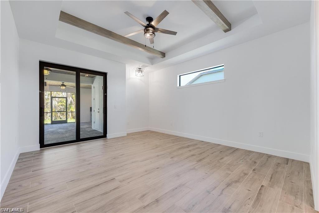Empty room with beamed ceiling, ceiling fan, plenty of natural light, and light hardwood / wood-style flooring