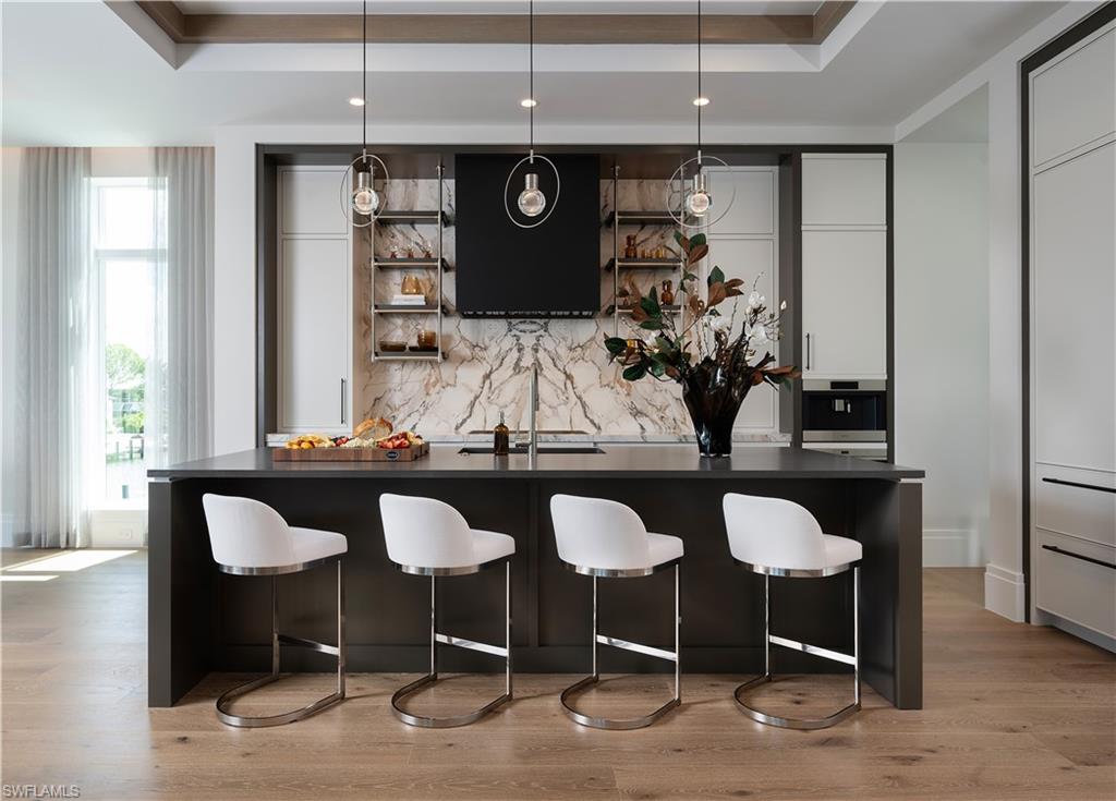 Contemporary kitchen featuring a dark island with a contrasting light countertop, a marble-patterned backsplash, and integrated appliances