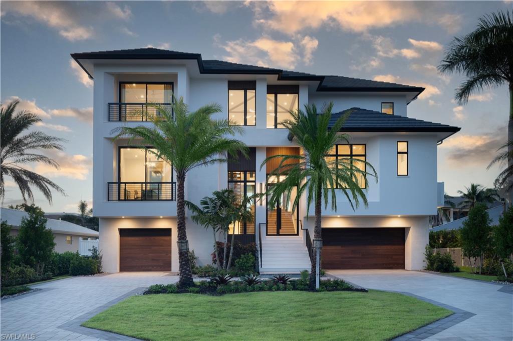 Modern multi-story residence featuring a white stucco exterior and black framed windows