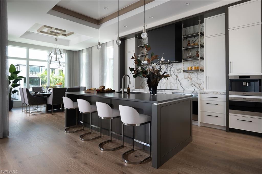Gourmet kitchen featuring a large central island with integrated seating, a waterfall countertop, and a built-in sink
