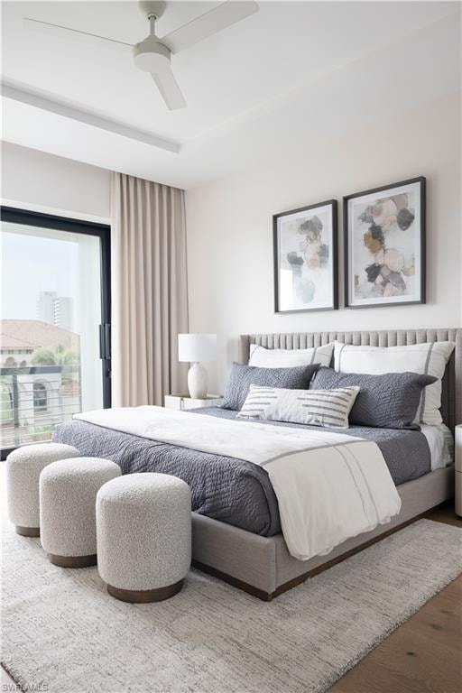 Spacious bedroom featuring wood-finish flooring, a contemporary ceiling fan, and a large sliding glass door with balcony access