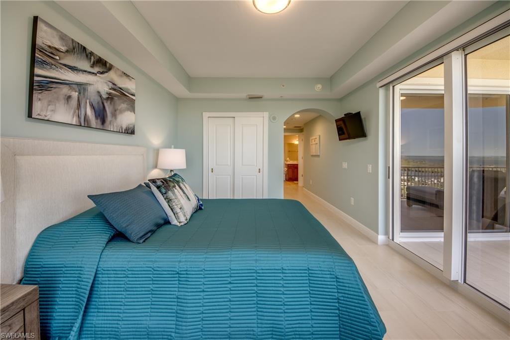 Spacious interior featuring wide plank wood-finish flooring, a tray ceiling, and a large sliding glass door opening to a private balcony