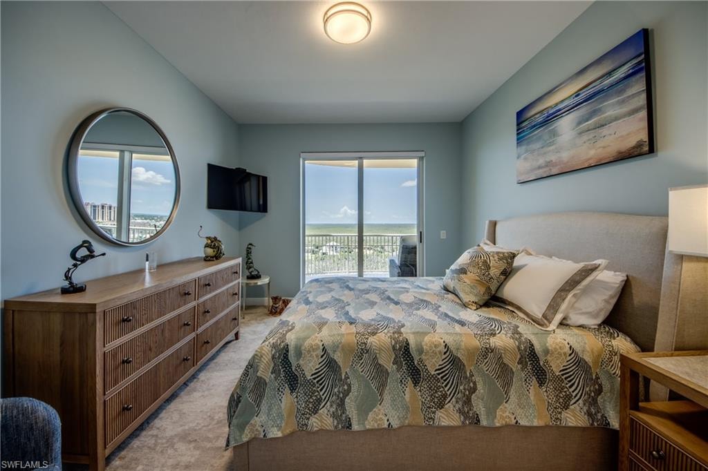 Bedroom featuring neutral carpeting, light blue walls, a ceiling-mounted light fixture, and a sliding glass door opening to an outdoor balcony