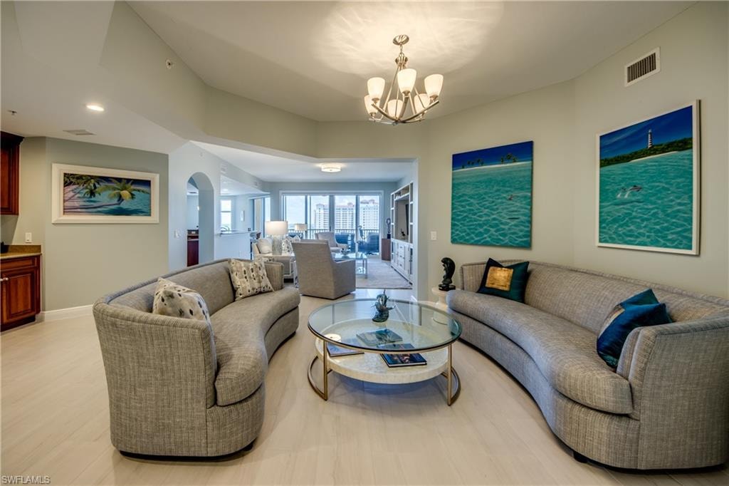 Spacious living area featuring light-toned wood-finish flooring, recessed lighting, and an elegant chandelier