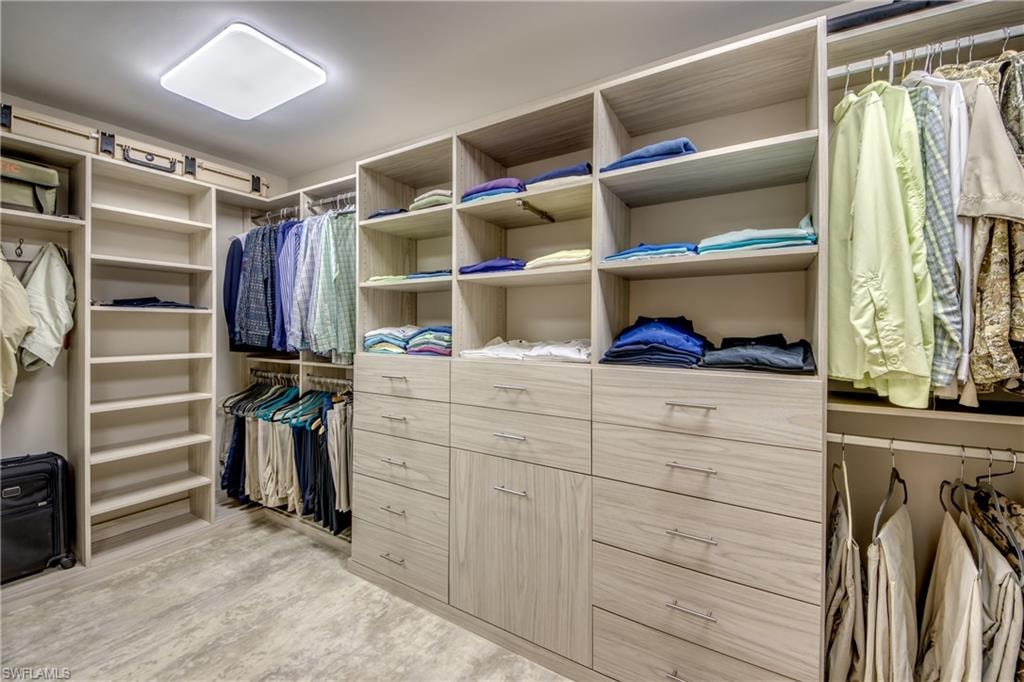 Walk-in closet featuring custom light wood-finish cabinetry