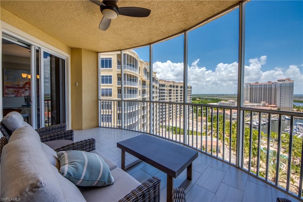 Expansive screened balcony featuring a ceiling fan and tile flooring
