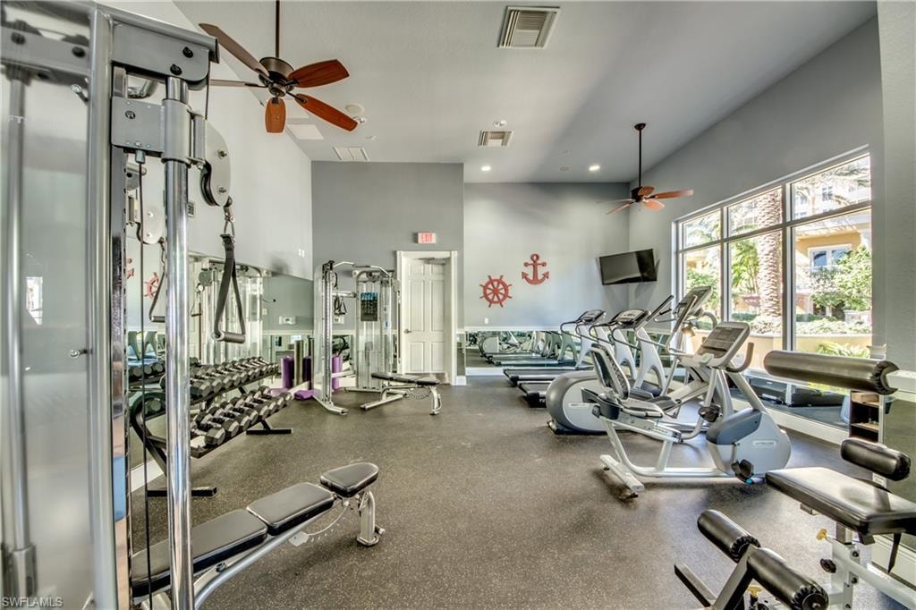 Spacious fitness center featuring high ceilings, large windows, and resilient flooring