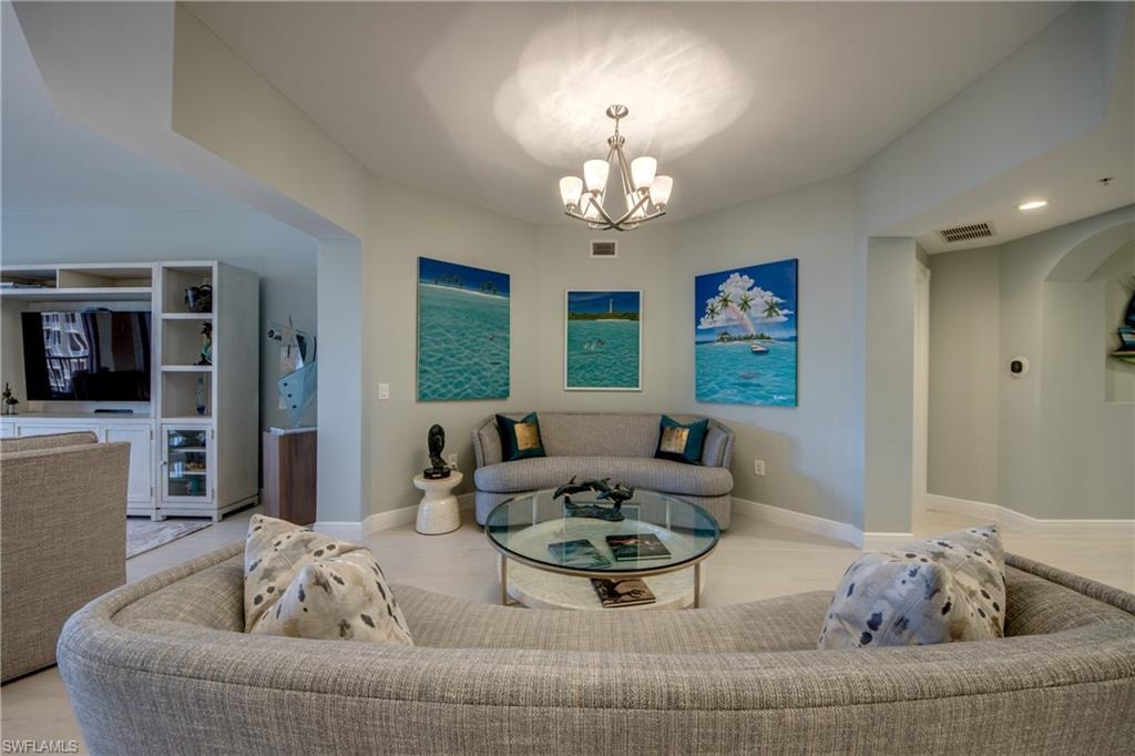 Recessed lighting illuminates the open-concept living space, featuring light-colored flooring and a contemporary chandelier