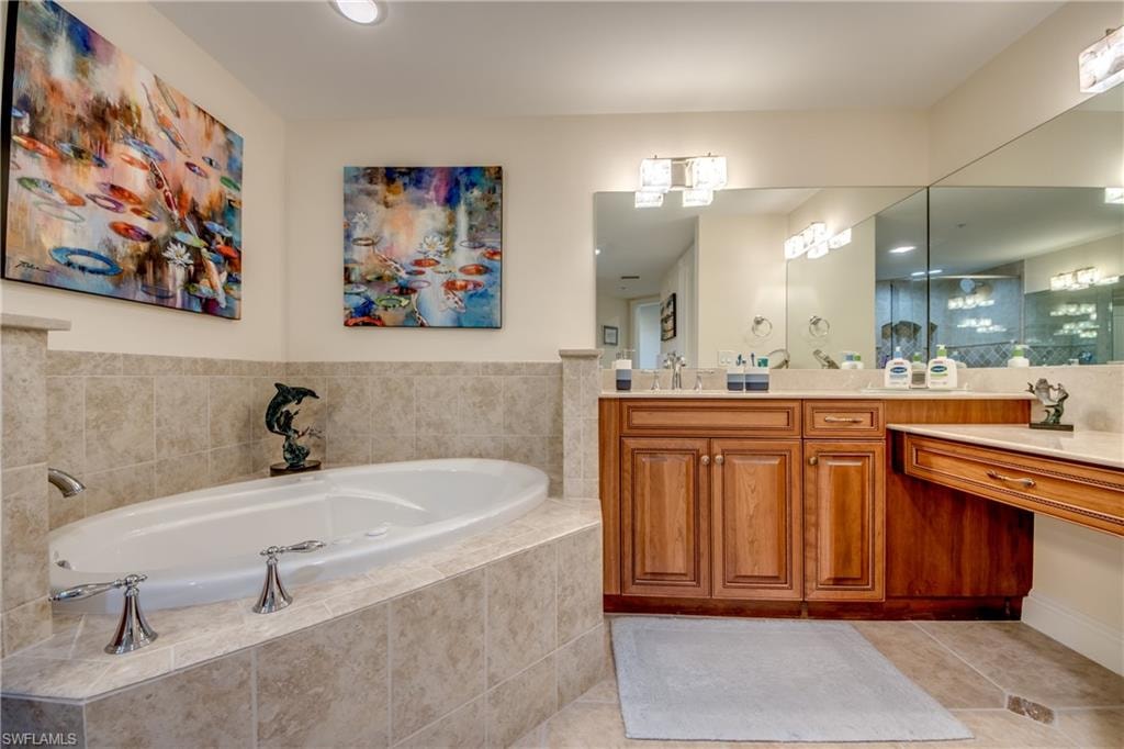 Master Bathroom featuring a built-in soaking tub with tile surround, a dual vanity with wood cabinetry, light-toned countertops, and a large wall-mounted mirror