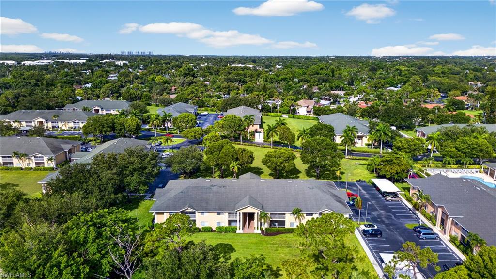 Expansive aerial perspective showcasing a multi-building residential community with lush green spaces, mature landscaping, and multiple covered parking areas