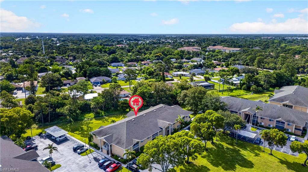 Community featuring multiple residential structures with gabled roofs, ample parking areas, and mature landscaping
