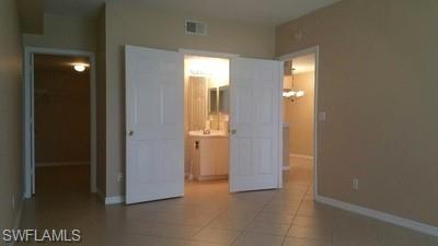 Spacious open-concept living area featuring tile flooring, multiple white panel doors, and abundant natural light from recessed ceiling fixtures and windows