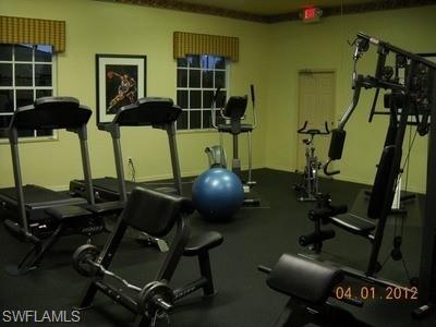 Dedicated fitness space with two windows, soft yellow wall paint, and dark flooring
